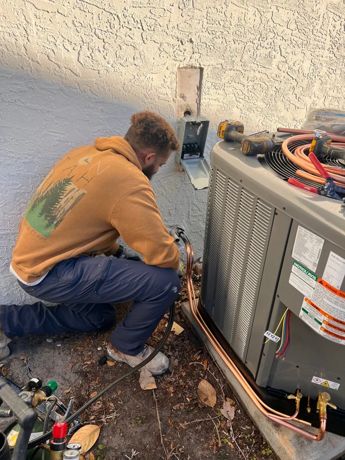 Donte Johnson servicing an air conditioning condenser on site