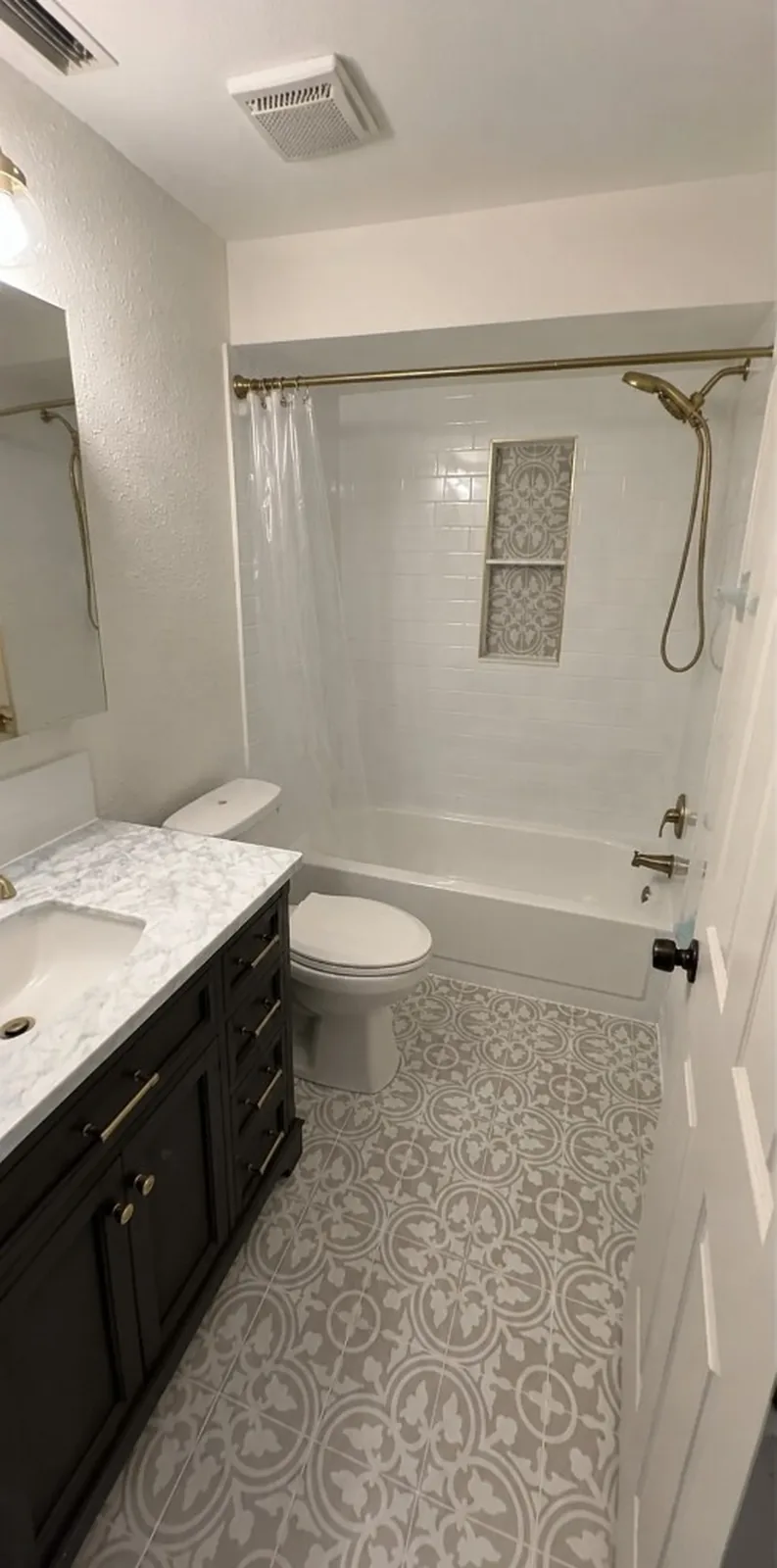Classic Bathroom Remodel after the work — a dark vanity with a marble top and patterned tile floor