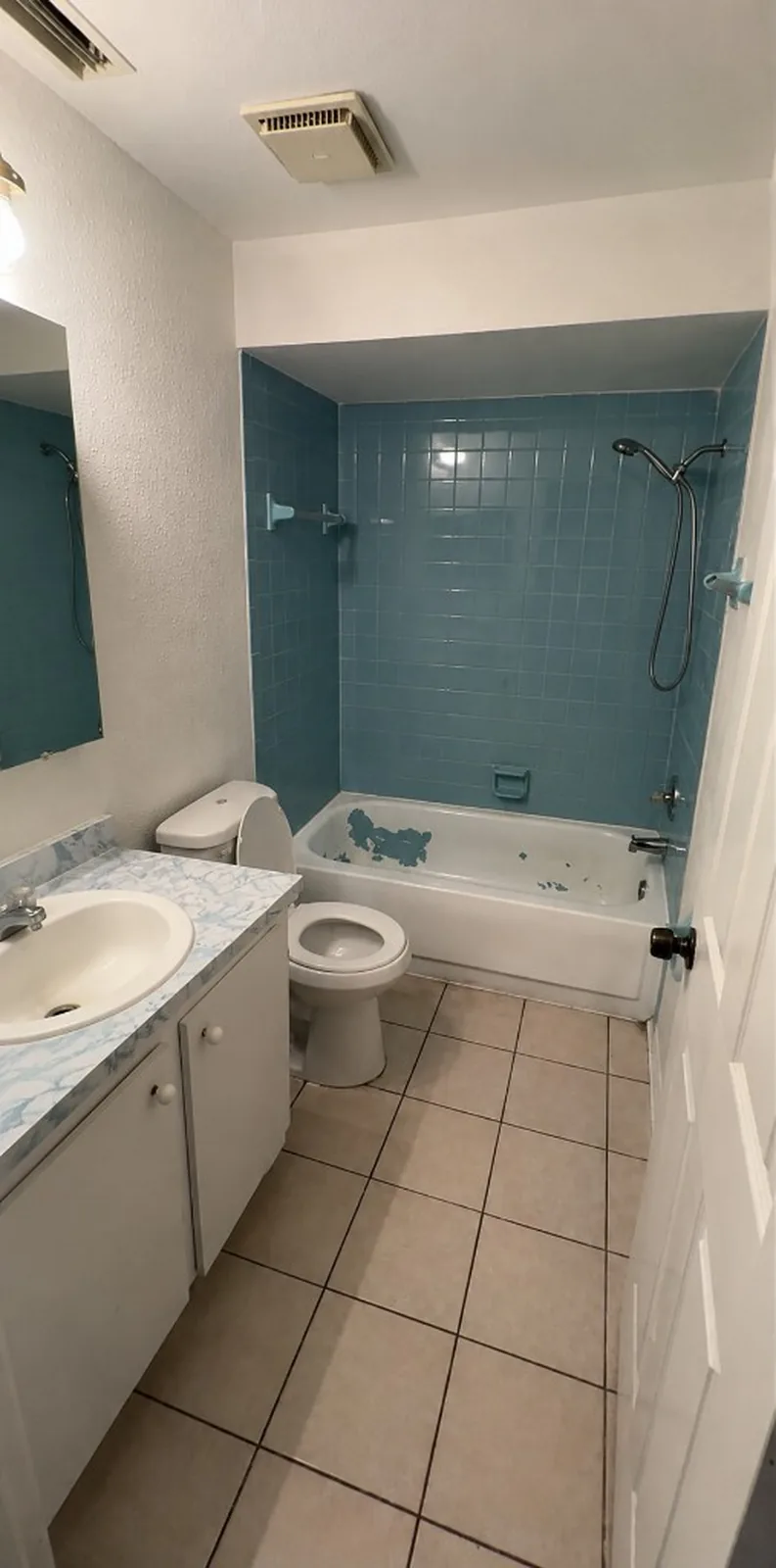 The same view before — blue wall tile and a worn vanity