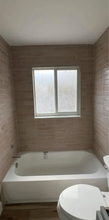 Tub & Surround Replacement after the work — a new tub with a fully tiled surround